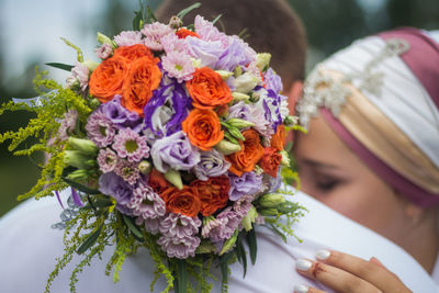 Close-up of bouquet on bridegroom back with bride during wedding