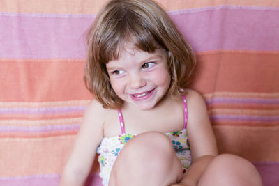 Close-up of smiling girl looking away while sitting on sofa