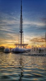 Ferris wheel by sea against sky during sunset