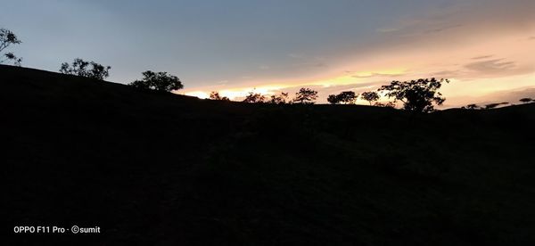 Silhouette trees on landscape against sky during sunset