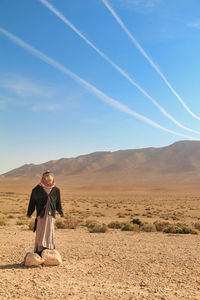 Man standing on desert against blue sky