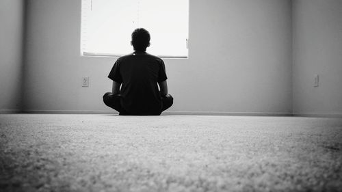 Rear view of man sitting on floor