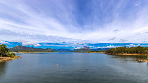 Scenic view of lake by mountains against blue sky