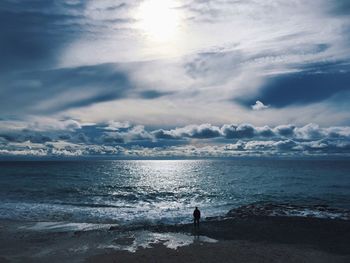 Silhouette man standing on beach against sky