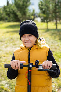 Boy rides an electric scooter in autumn park. schoolboy using e-scooter at sunny day.