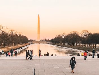 People at monument against clear sky during sunset