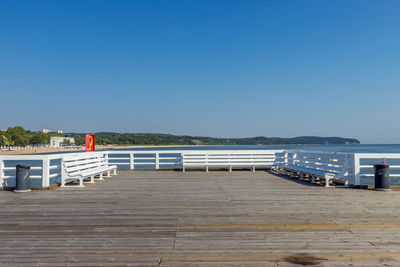 Pier over sea against clear blue sky