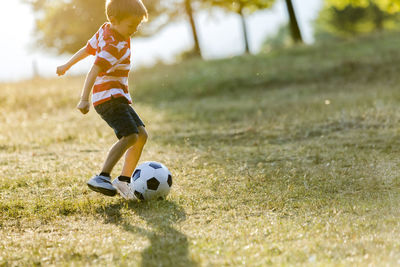 Little boy playing soccer on a meadow
