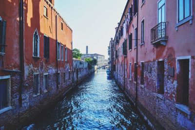 Canal amidst buildings in city against sky