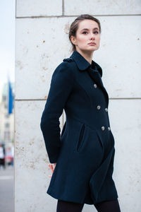 Portrait of woman standing against wall