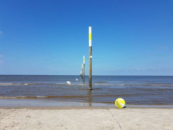 Yellow umbrella on beach against clear blue sky