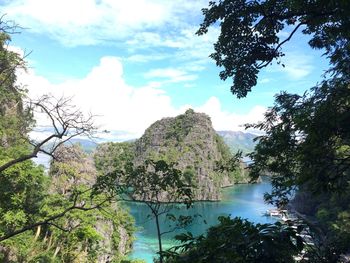 Scenic view of sea by trees against sky