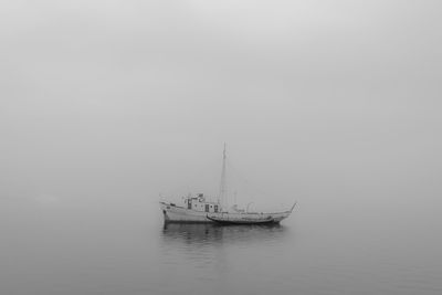 Sailboat sailing in sea against sky during foggy weather