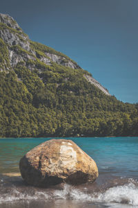 Rocks by sea against clear blue sky