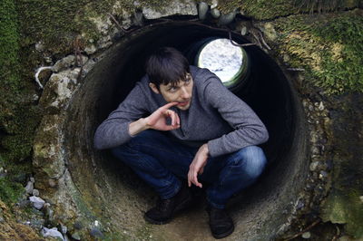 Mid adult man crouching in cement pipe