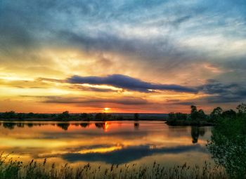 Scenic view of lake against dramatic sky during sunset