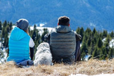 Rear view of people sitting on field during winter