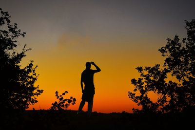 Silhouette person standing on field against sky during sunset