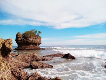 Rock formation on beach against sky