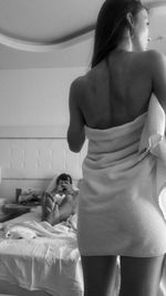 Rear view of woman standing on bed