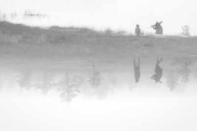 People standing by trees against clear sky