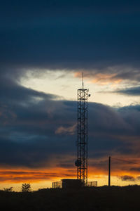 Low angle view of electricity pylon against sky during sunset