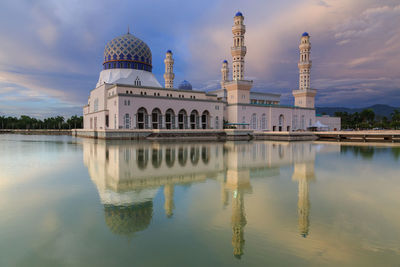 Mosque by lake against sky