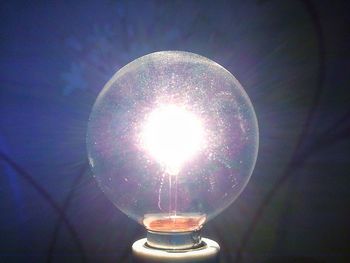 Close-up of illuminated light bulb against sky