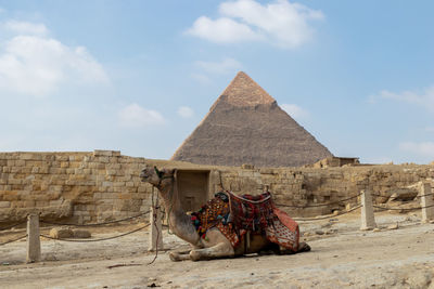 Rear view of man sitting on rock against sky