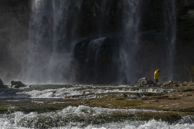 Man standing by waterfall outdoors