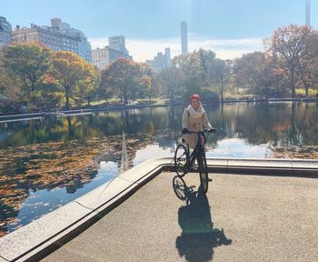 Portrait of woman riding bicycle against lake