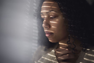 Pensive young woman looking through window