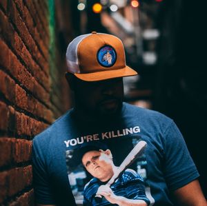 Portrait of man wearing hat standing against wall