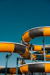 Low angle view of water slide against clear sky at amusement park