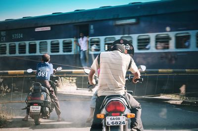 Rear view of people riding motorcycle on road