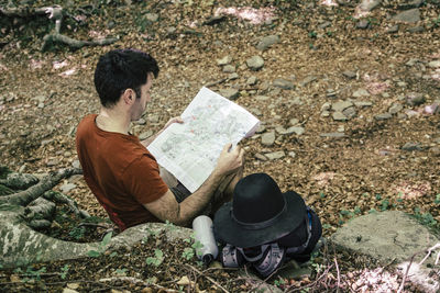 Man reading map while sitting in forest