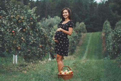 Full length portrait of young woman standing on field