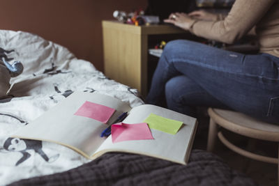 Adhesive notes on diary over bed by businesswoman working at home