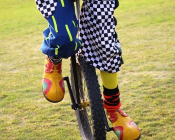 Low section of joker riding unicycle on grass