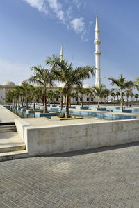 Palm trees by swimming pool against sky