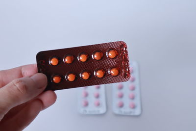 Close-up of hand holding cup over white background
