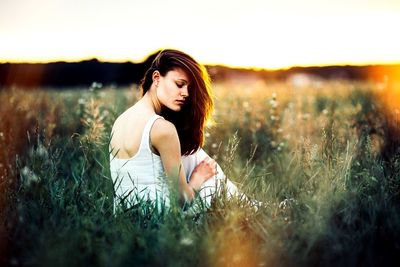 Woman standing on field at sunset