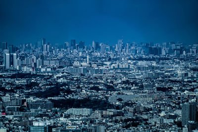 High angle view of illuminated buildings in city against blue sky