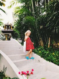 Full length of girl walking on staircase by palm trees