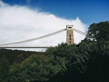 Low angle view of suspension bridge against cloudy sky