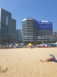 People on beach against buildings in city