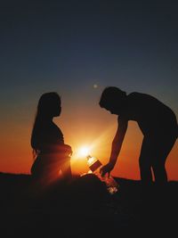 Silhouette couple against orange sky during sunset