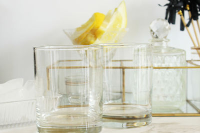 Empty drinking glasses with bottle and lemon slice on marble table