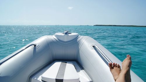 Low section of woman on boat sailing in sea against clear sky