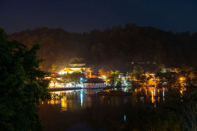 Illuminated buildings by lake at night